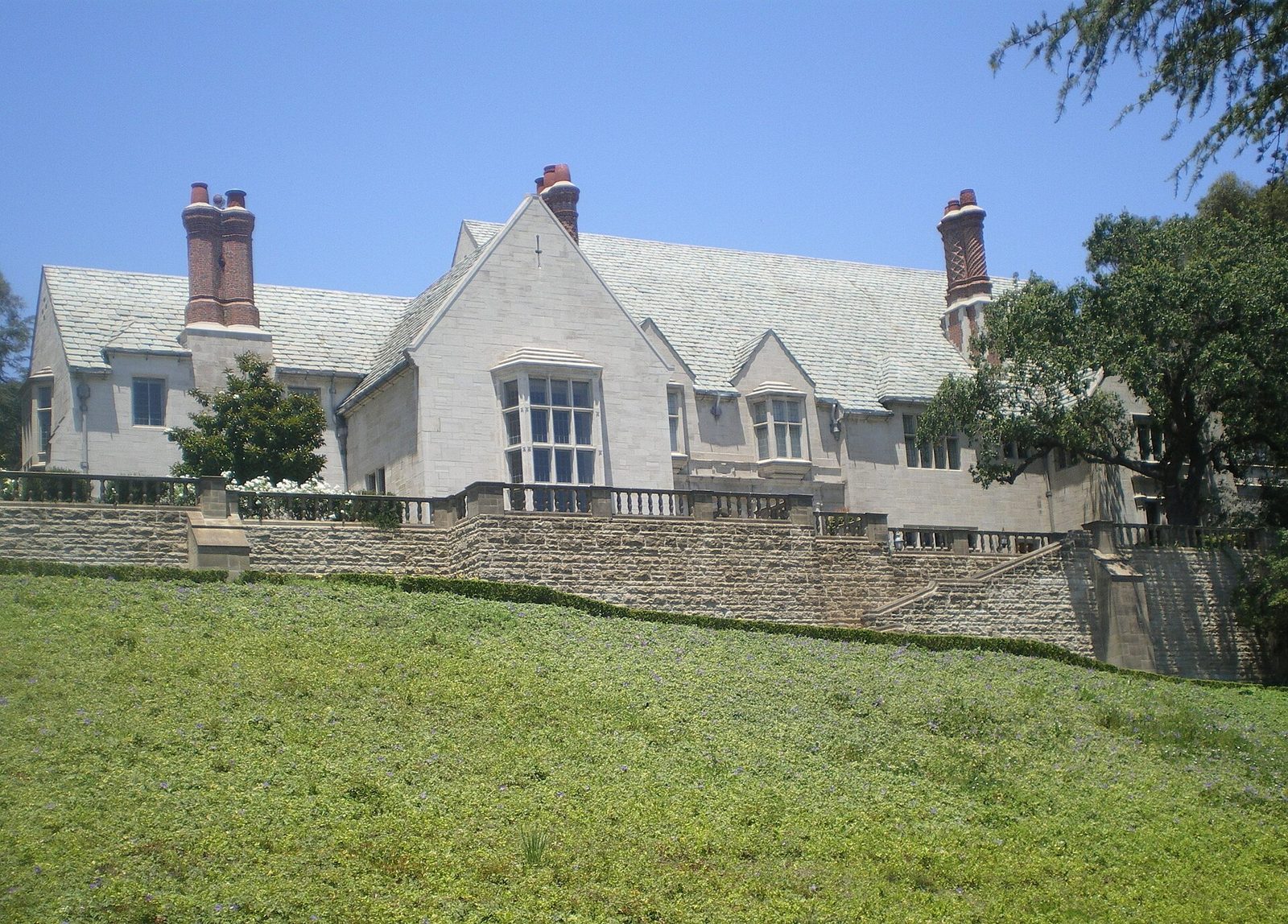 Large gray stone Tudor mansion above a lawn