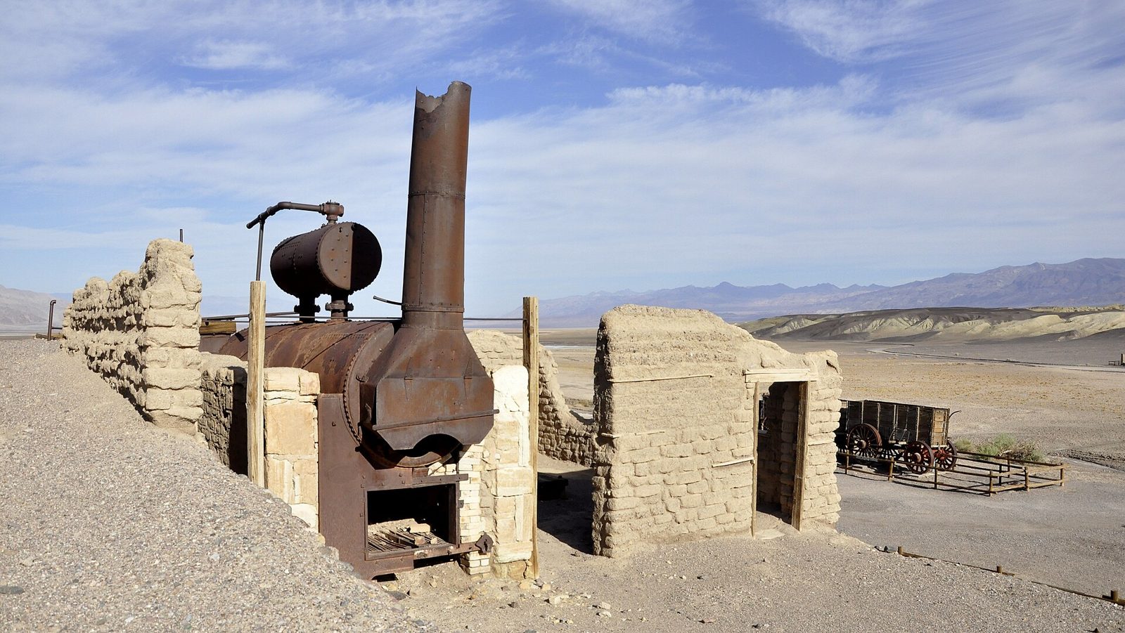 Adobe ruins and an old ore wagon on a desert flat
